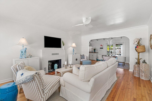 living room featuring light wood-type flooring, ceiling fan, and ornamental molding