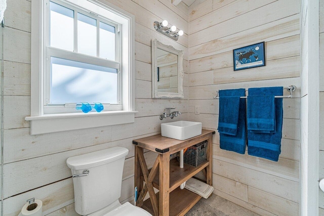 bathroom with vanity, wood walls, and toilet