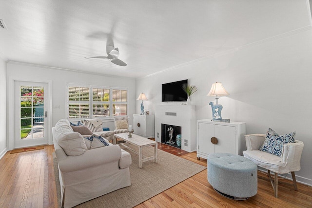 living room featuring light wood-type flooring, ceiling fan, and ornamental molding