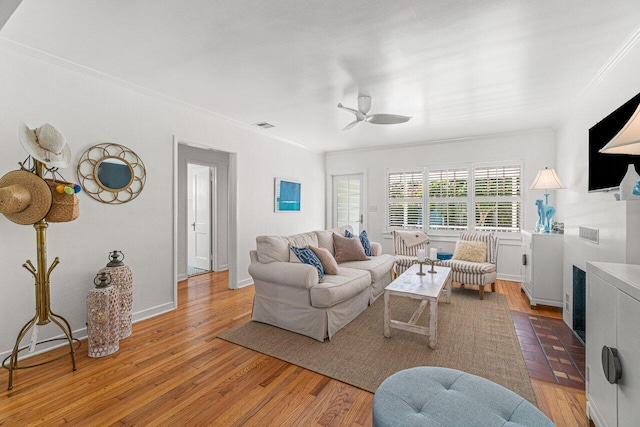 living room featuring light wood-type flooring, ceiling fan, and ornamental molding