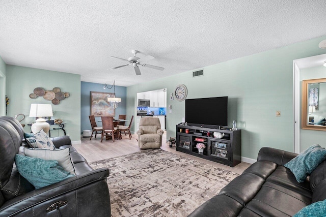 living room with ceiling fan, light hardwood / wood-style floors, and a textured ceiling