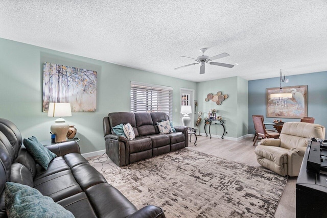 living room featuring ceiling fan, light hardwood / wood-style flooring, and a textured ceiling