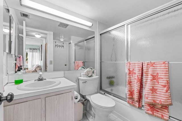 full bathroom with combined bath / shower with glass door, vanity, tile patterned floors, and toilet