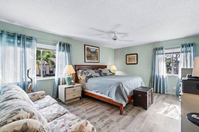 bedroom with ceiling fan, light hardwood / wood-style flooring, and a textured ceiling