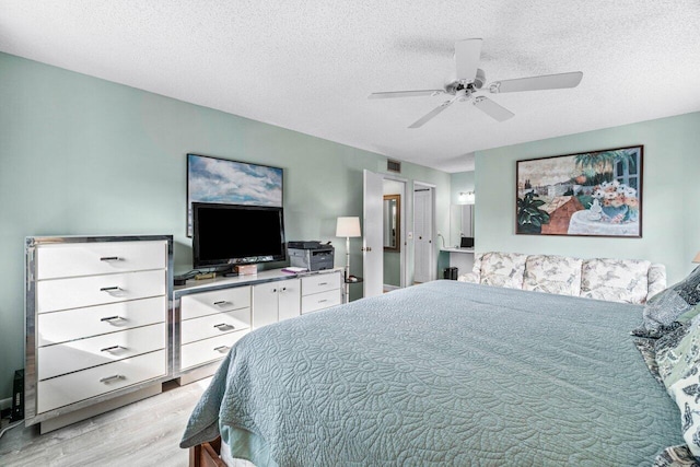 bedroom with ceiling fan, light hardwood / wood-style floors, and a textured ceiling