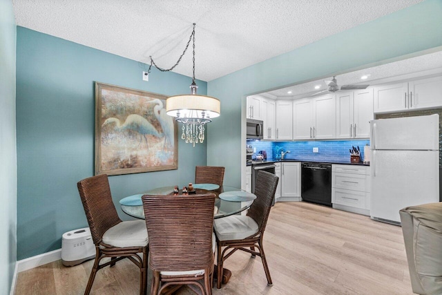 dining area with sink, a textured ceiling, and light wood-type flooring