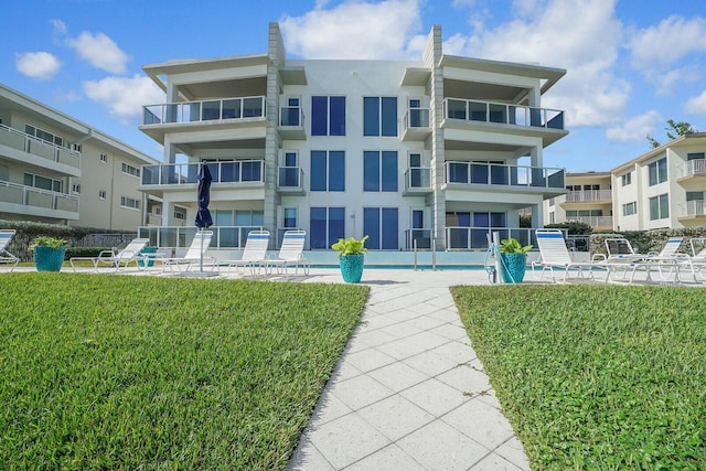 back of house with a yard and a community pool