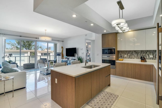 kitchen featuring white cabinets, oven, sink, tasteful backsplash, and decorative light fixtures