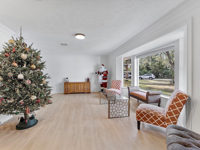 sitting room featuring crown molding, a textured ceiling, and light hardwood / wood-style floors