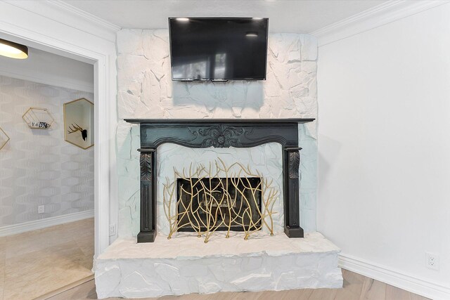 living room featuring crown molding, a stone fireplace, and hardwood / wood-style floors