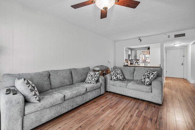 living room featuring a textured ceiling, hardwood / wood-style flooring, and ceiling fan