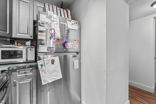 kitchen featuring appliances with stainless steel finishes, gray cabinets, and dark wood-type flooring