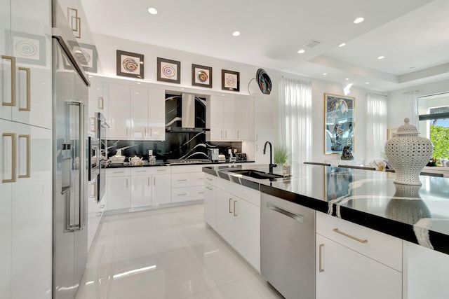 kitchen with sink, stainless steel dishwasher, tasteful backsplash, a tray ceiling, and white cabinetry