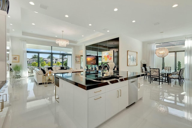 kitchen with decorative light fixtures, white cabinetry, a center island with sink, and sink