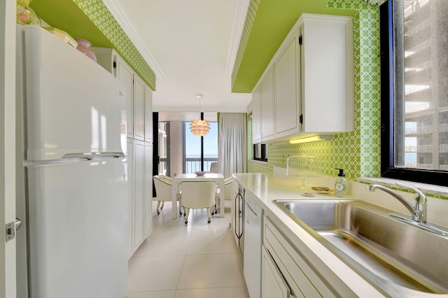 kitchen with white cabinets, white appliances, hanging light fixtures, and sink