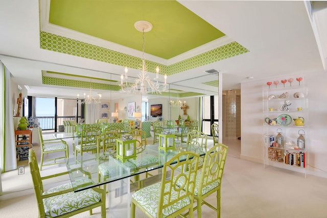 carpeted dining area featuring a notable chandelier, a raised ceiling, and ornamental molding