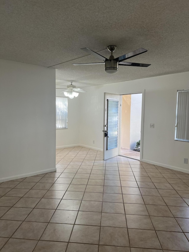 empty room with light tile patterned floors, a textured ceiling, and ceiling fan