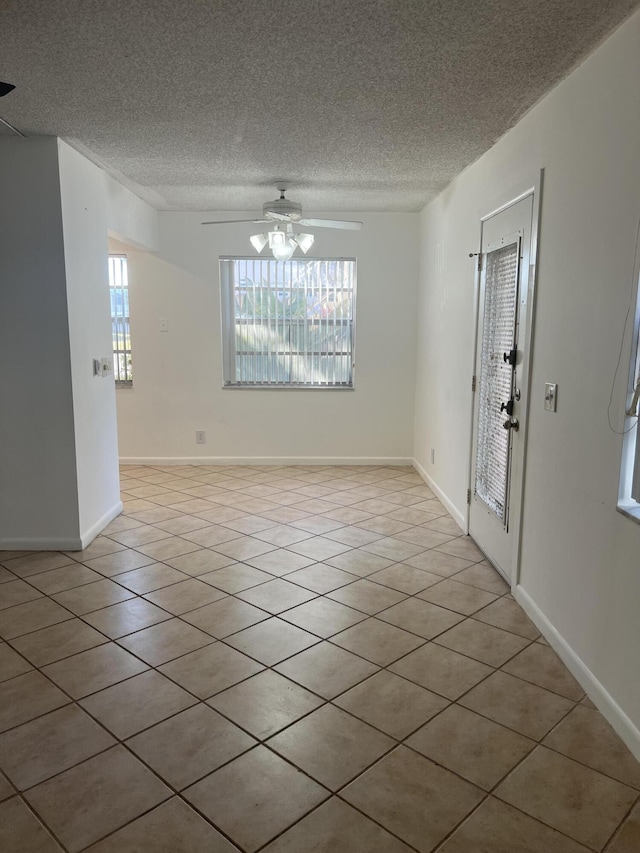 tiled empty room with ceiling fan and a textured ceiling