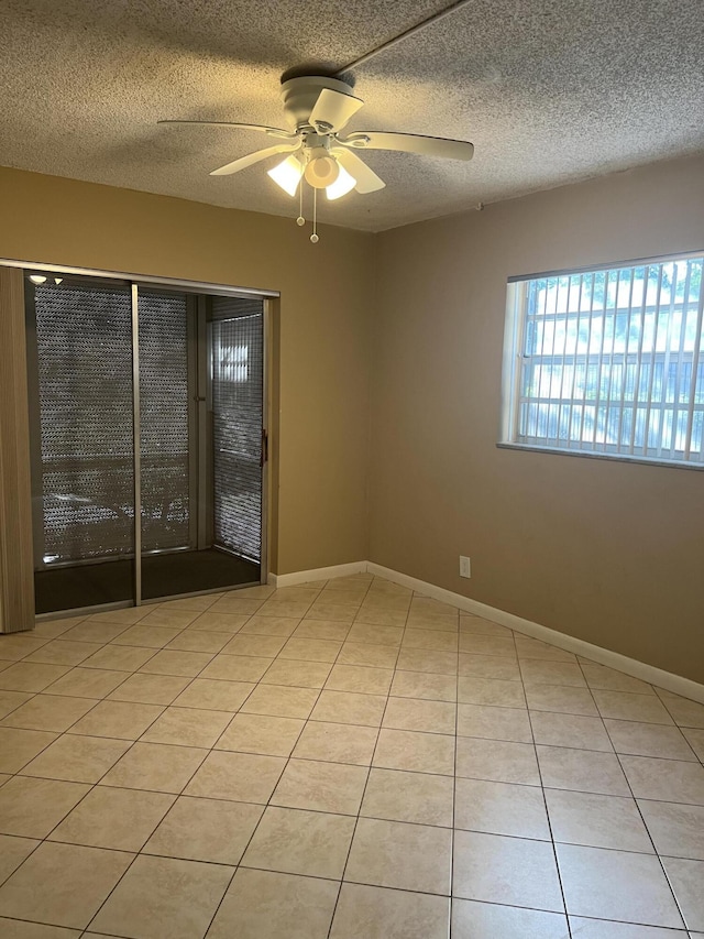 empty room featuring light tile patterned floors, a textured ceiling, and ceiling fan