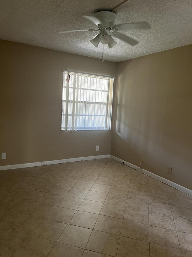 unfurnished room with ceiling fan, light tile patterned floors, and a textured ceiling