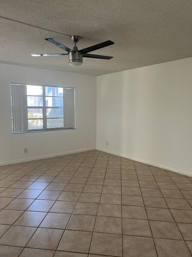 tiled empty room with ceiling fan and a textured ceiling