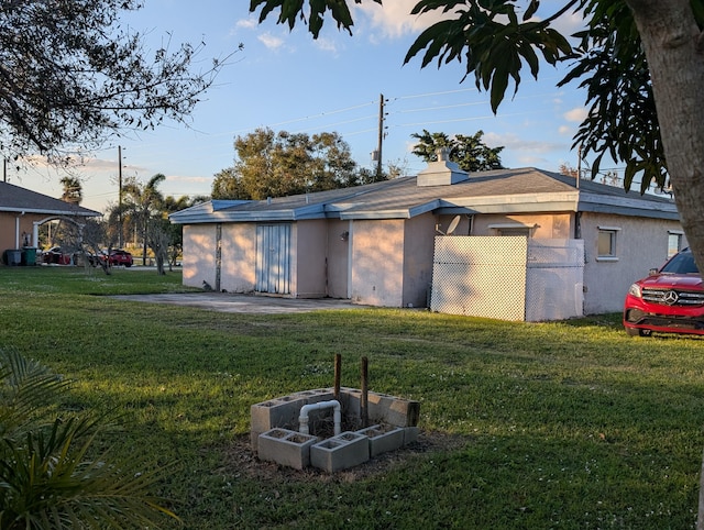 back of house featuring an outdoor fire pit and a yard