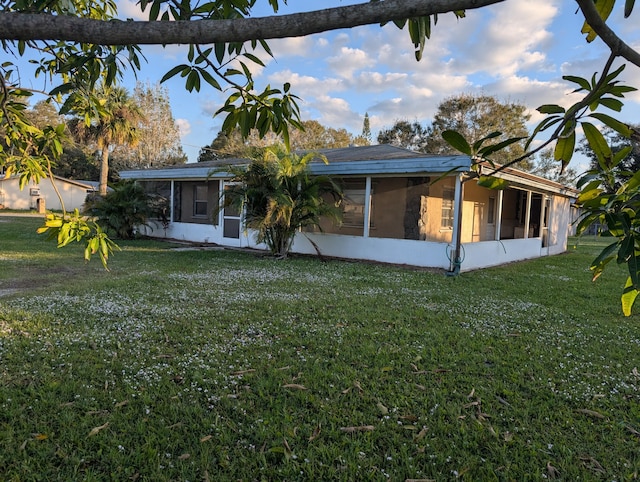 rear view of house with a sunroom and a lawn