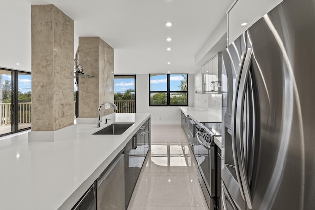 kitchen featuring appliances with stainless steel finishes, light countertops, a sink, and modern cabinets