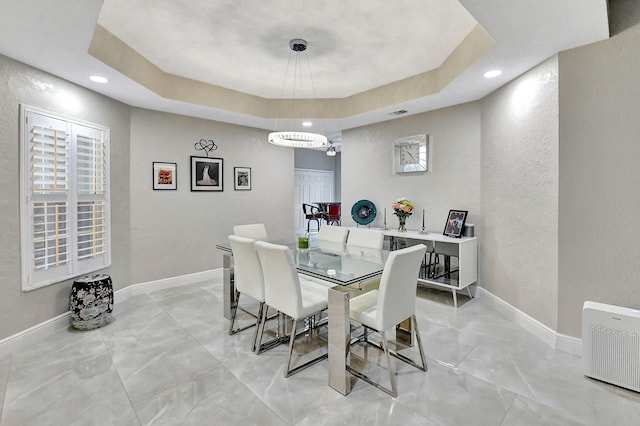 dining space featuring a raised ceiling and an inviting chandelier