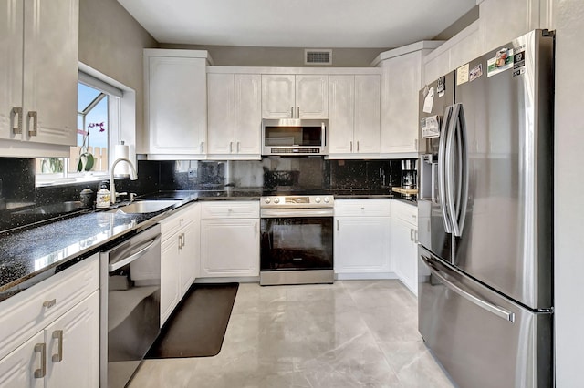 kitchen with white cabinetry, sink, appliances with stainless steel finishes, and dark stone counters