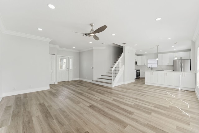 unfurnished living room with ceiling fan, sink, ornamental molding, and light wood-type flooring