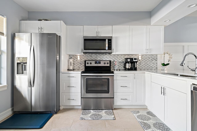 kitchen with white cabinets, light tile patterned floors, stainless steel appliances, and sink