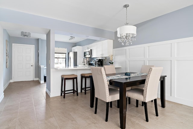 tiled dining room with sink and a notable chandelier