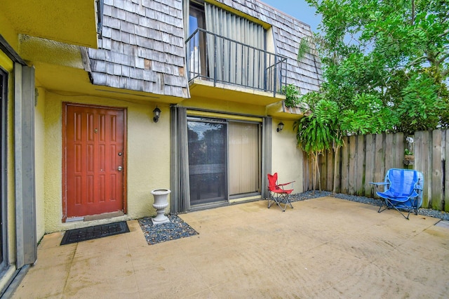 view of exterior entry featuring a patio and a balcony