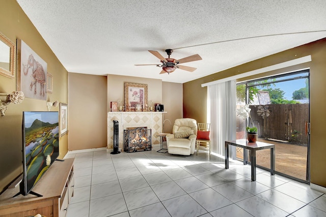 sitting room with a tiled fireplace, light tile patterned floors, and a textured ceiling