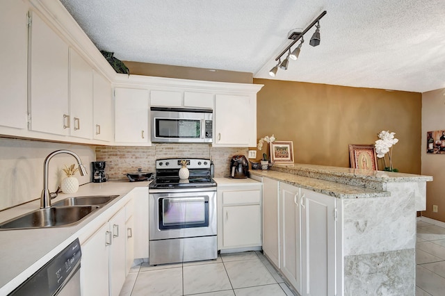 kitchen featuring white cabinetry, sink, rail lighting, kitchen peninsula, and appliances with stainless steel finishes