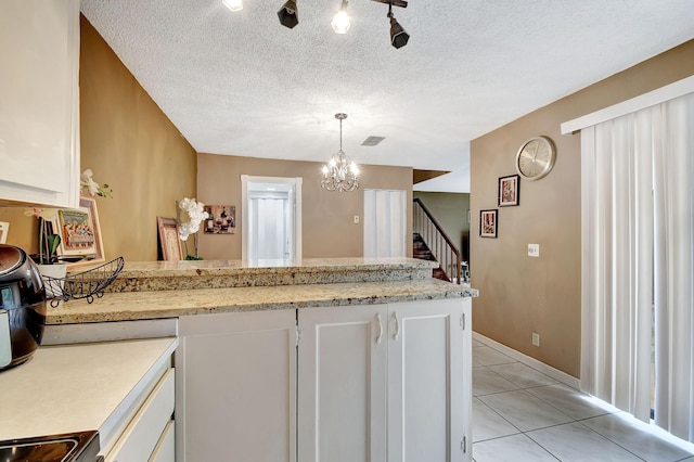 kitchen featuring pendant lighting, a textured ceiling, white cabinetry, and light tile patterned floors