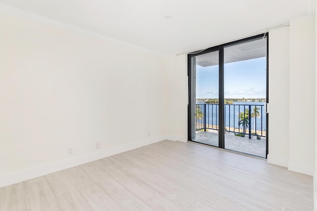 empty room featuring expansive windows, a water view, light hardwood / wood-style floors, and ornamental molding