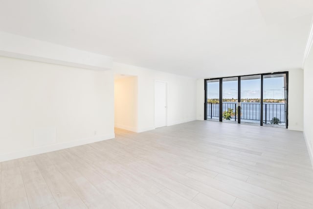 empty room with light wood-type flooring and a wall of windows