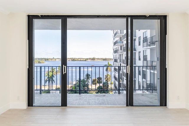 doorway to outside featuring floor to ceiling windows, french doors, a water view, and plenty of natural light