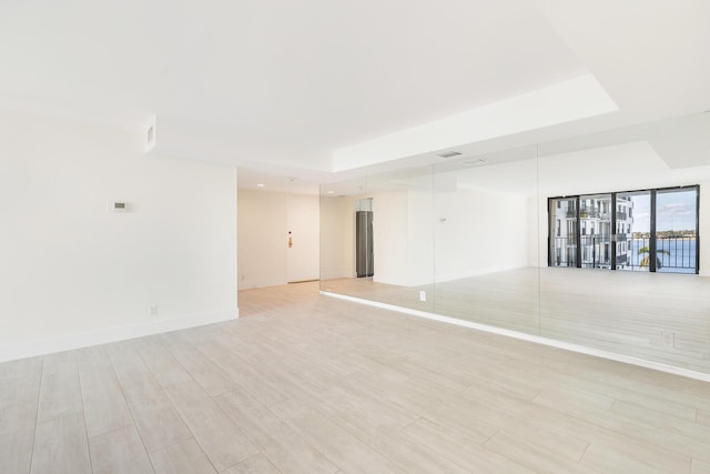 unfurnished room featuring light hardwood / wood-style floors and a raised ceiling