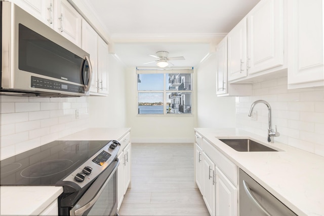 kitchen with backsplash, sink, ceiling fan, appliances with stainless steel finishes, and white cabinetry