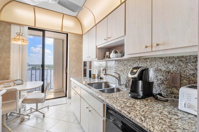 kitchen with dishwasher, light stone counters, light tile patterned floors, and sink