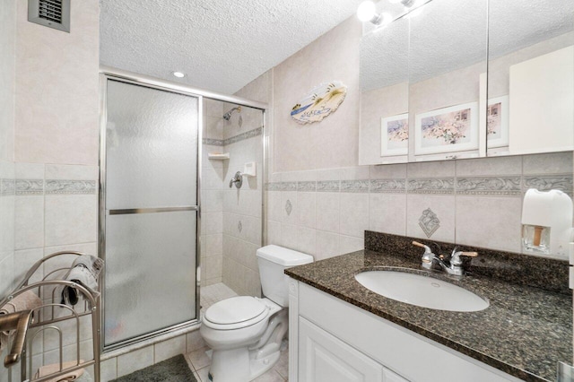 bathroom featuring tile patterned floors, a textured ceiling, toilet, a shower with shower door, and tile walls