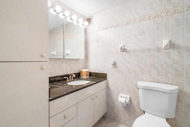 bathroom featuring vanity, toilet, and tile walls