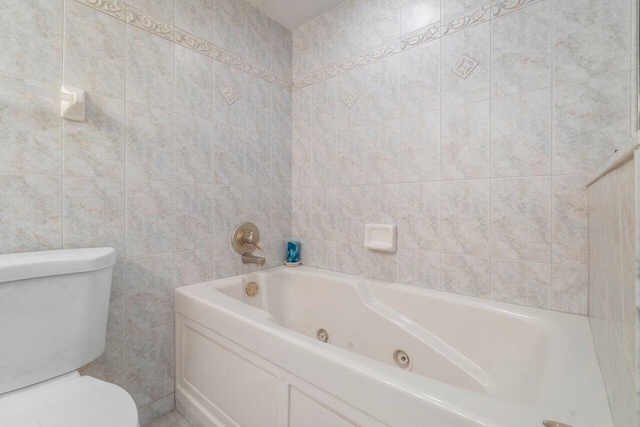 bathroom with a washtub, toilet, and tile walls