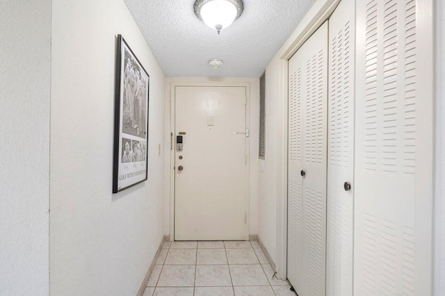 doorway to outside featuring light tile patterned flooring and a textured ceiling