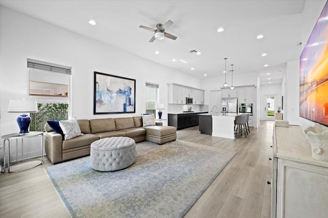 living room featuring a healthy amount of sunlight, sink, ceiling fan, and light hardwood / wood-style floors