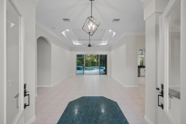 interior space with a chandelier, ornamental molding, light tile patterned floors, and a tray ceiling