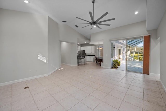 unfurnished living room featuring ceiling fan with notable chandelier, light tile patterned floors, and high vaulted ceiling